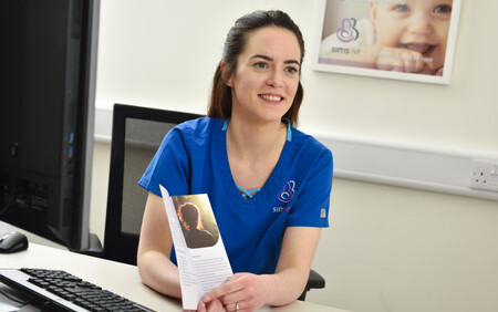 Nurse sittinf down and showing a brochure to someone out of shot
