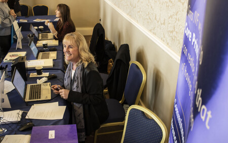 Woman sitting down at computer smiling at someone out of shot