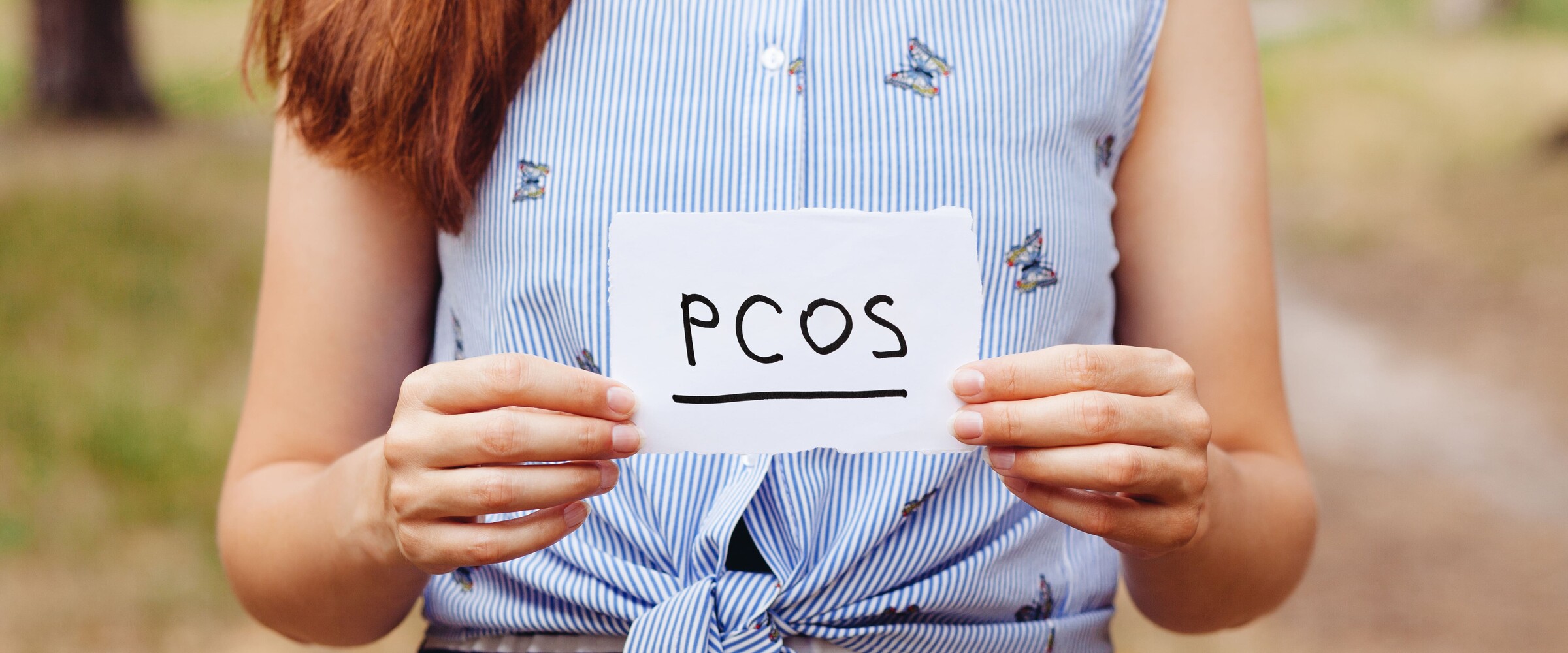 Woman holding a sign saying PCOS