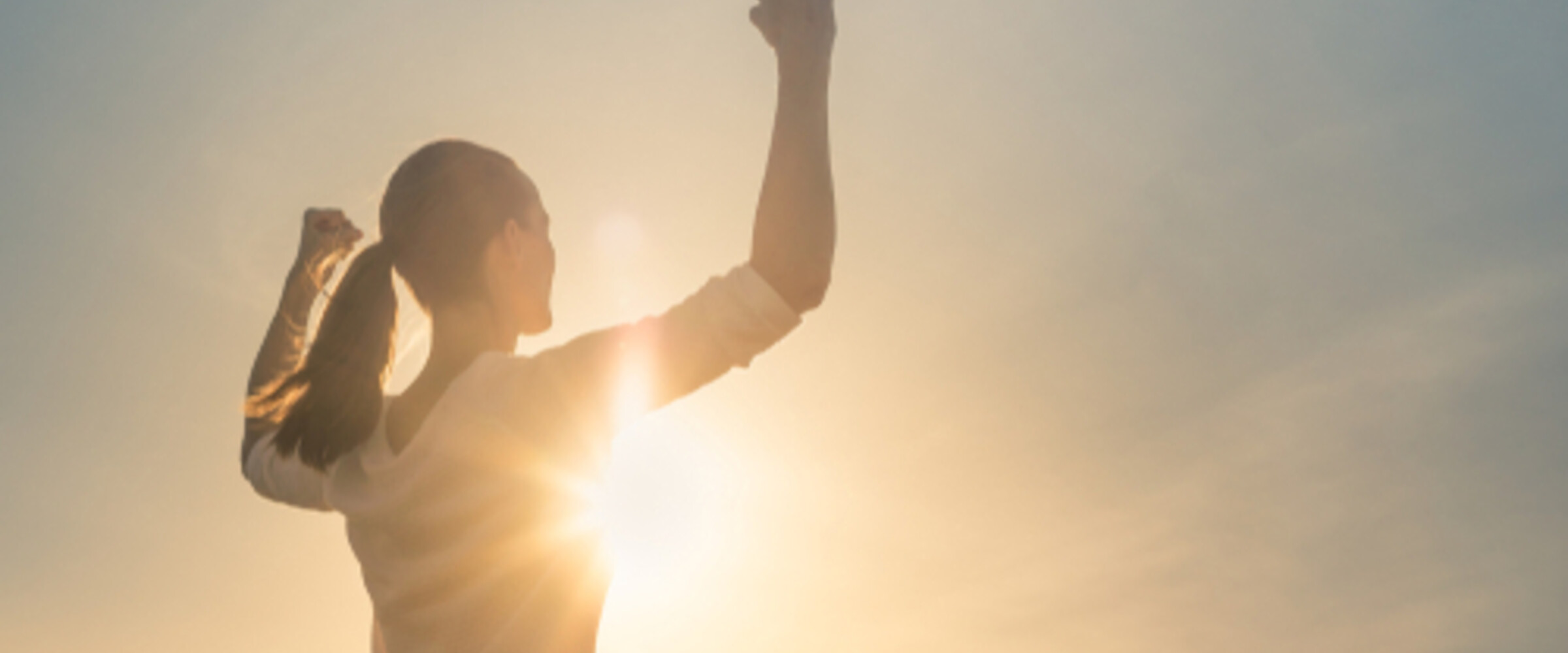 strong woman lifting her arms up to the sun