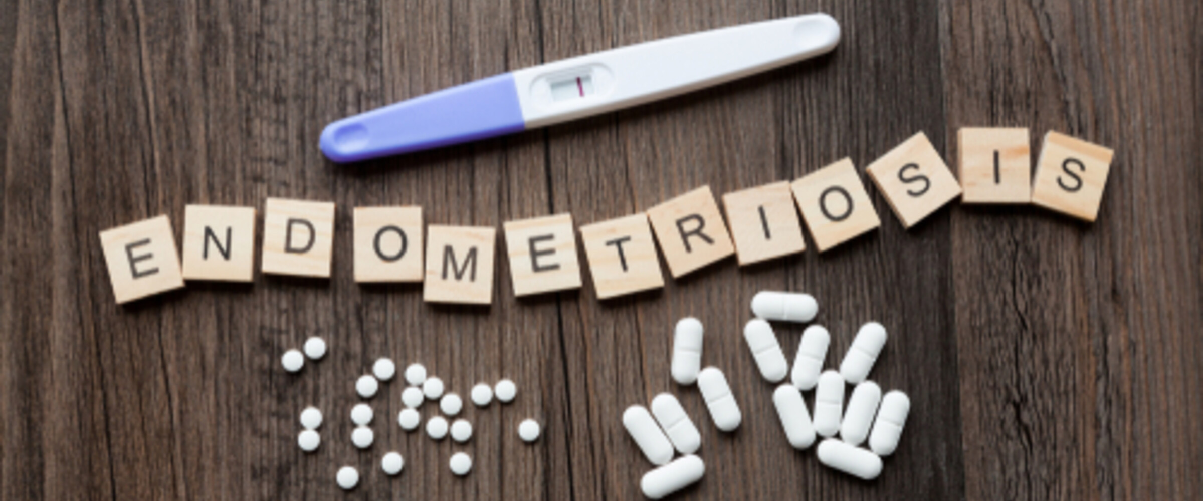 pregnancy test, pills and tiles spelling out endometriosis
